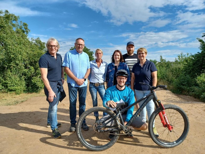 Stolz auf die neue Pumptrack-Anlage - das Projektteam, von links nach rechts: Bürgermeister Stefan Veth, Ortsbürgermeister Walter Schmitt, Jugendpflegerin Pia Thomé-Schulz, Verbandsgemeinde-Beigeordnete Marion Strese, Bauamtsmitarbeiter Marc Lindenzweig, Bauamtsleitung Annette Roos-Seidenspinner; vorne: Felix Lapport von Shapetastic Crew.