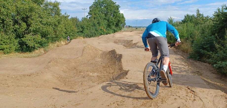 Bild eines Bikers, der über die neue Pumptrack-Anlage der Verbandsgemeinde in Hochdorf-Assenheim, am Mutterstadter Weg fährt.
