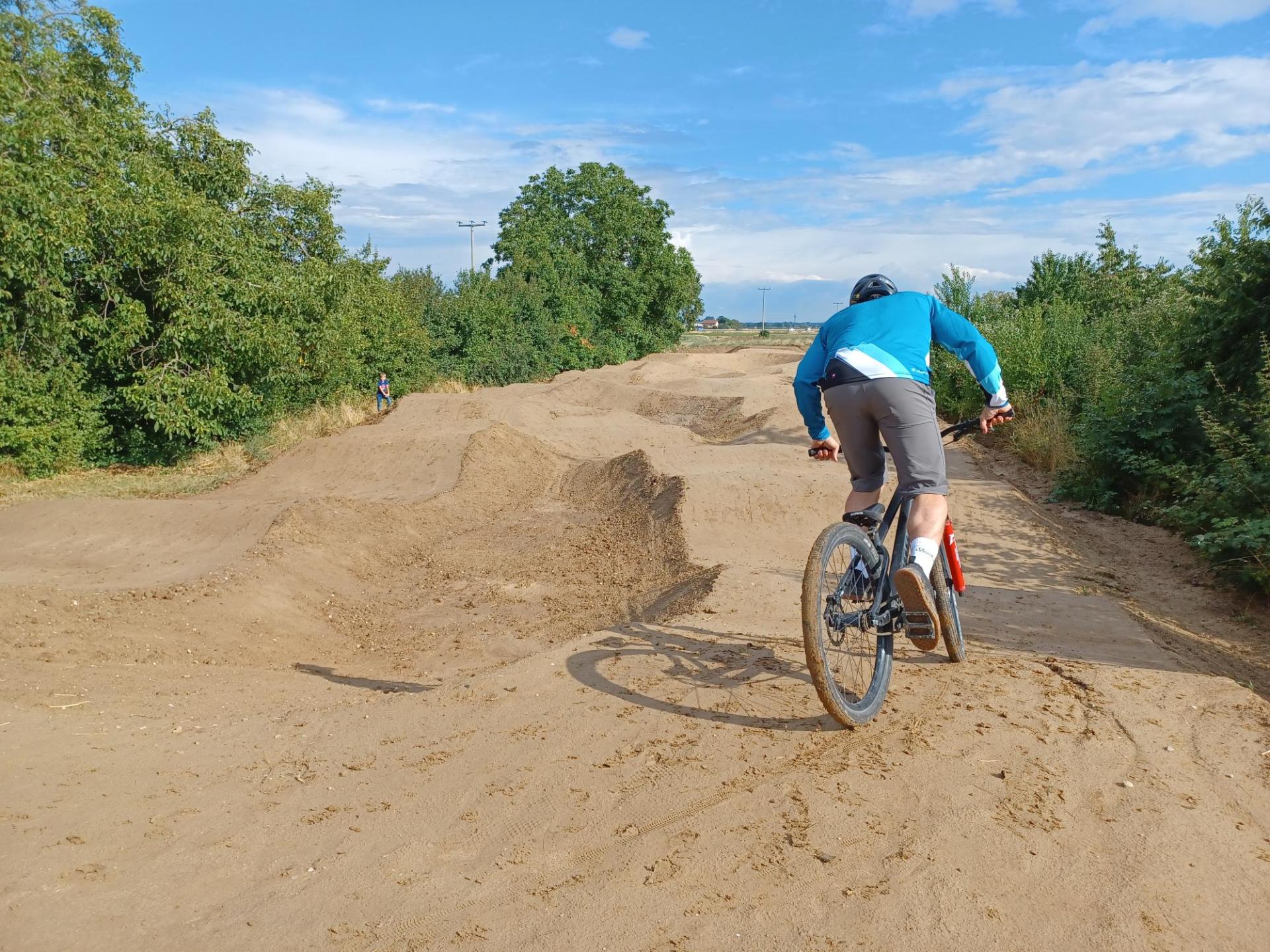 Bild eines Bikers, der über die neue Pumptrack-Anlage der Verbandsgemeinde in Hochdorf-Assenheim, am Mutterstadter Weg fährt.